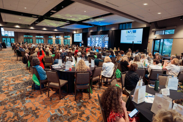 Cambria Jacobs on stage in front of a full conference room at a CSA event